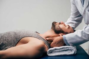A chiropractor uses a stainless steel instrument on a patient's forearm during therapy.